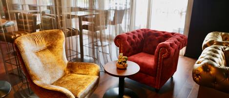 Un interno moderno con una poltrona in velluto rosso, una poltrona vintage e un piccolo tavolino con un oggetto decorativo.