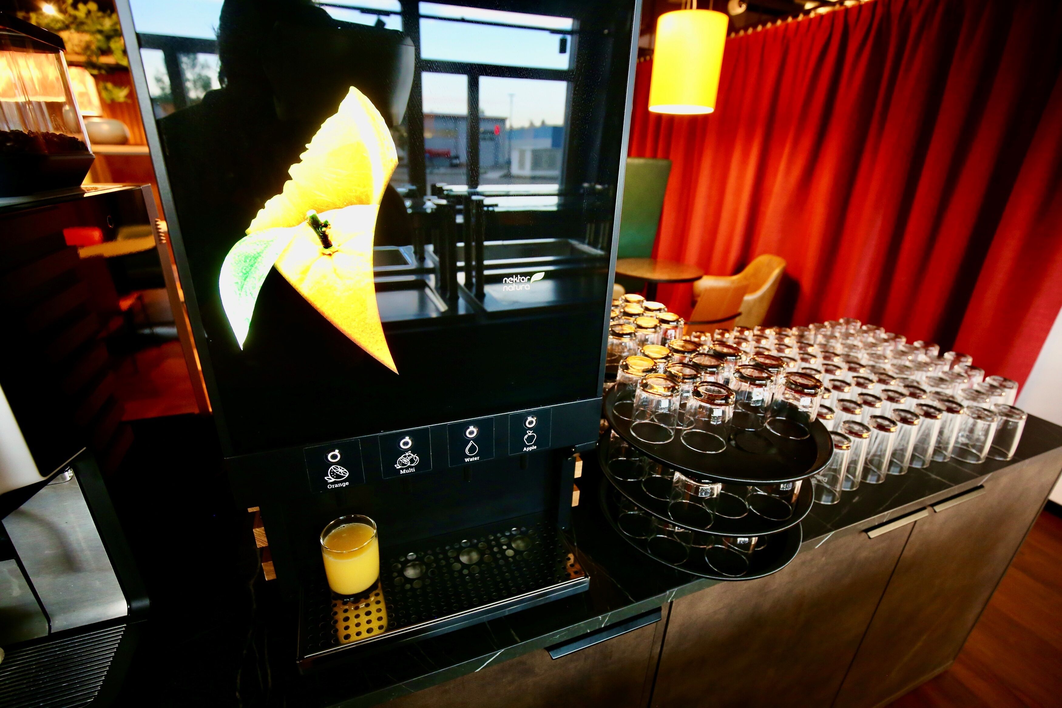 A coffee machine with a digital display, a coffee cup, and a tray of shot glasses.