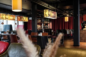 Un restaurante con mesas y sillas, obras de arte colgadas y una zona de bar.
