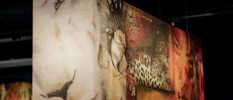 Una obra de arte grande, de varios paneles, con diversos elementos abstractos y figurativos, incluyendo un rostro y un estampado de leopardo.