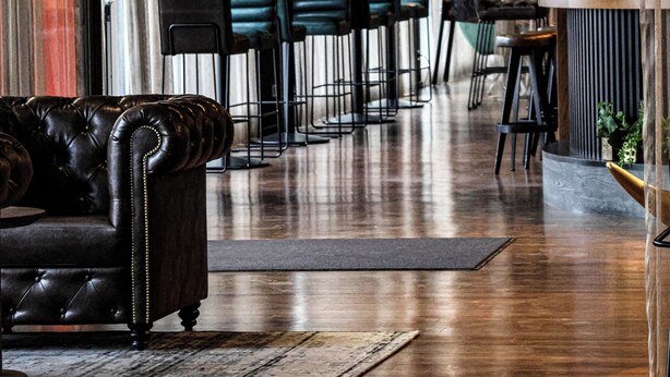 Un intérieur moderne avec un canapé en cuir, des tabourets de bar et un coin repas.