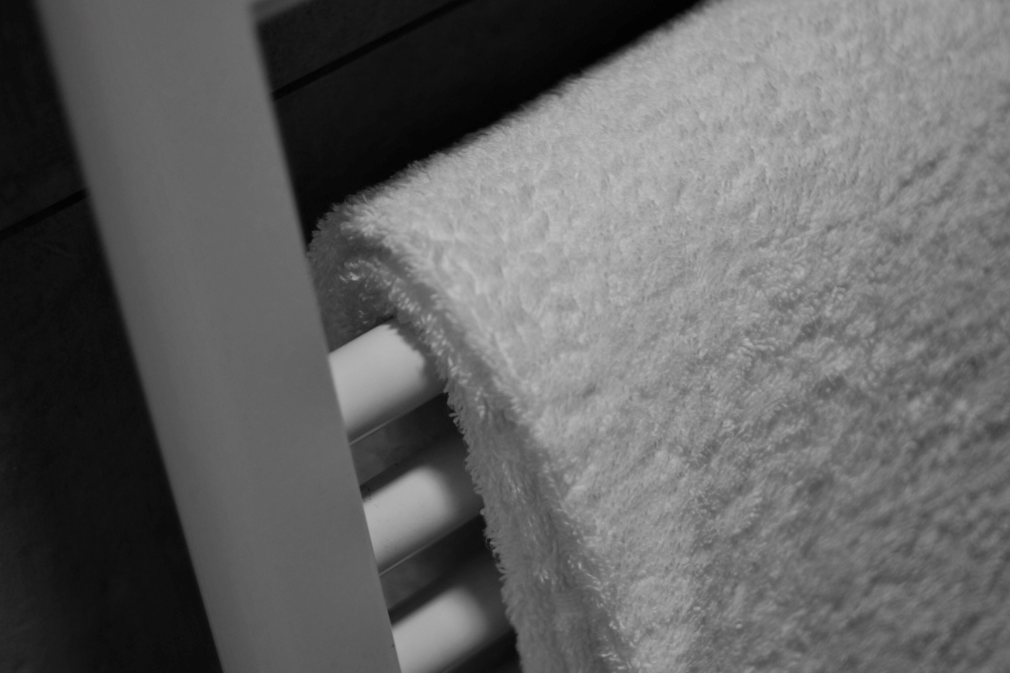 A white towel draped over a white radiator.