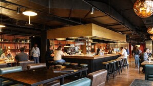 Un restaurant avec des tables hautes, des tabourets de bar et un espace bar.