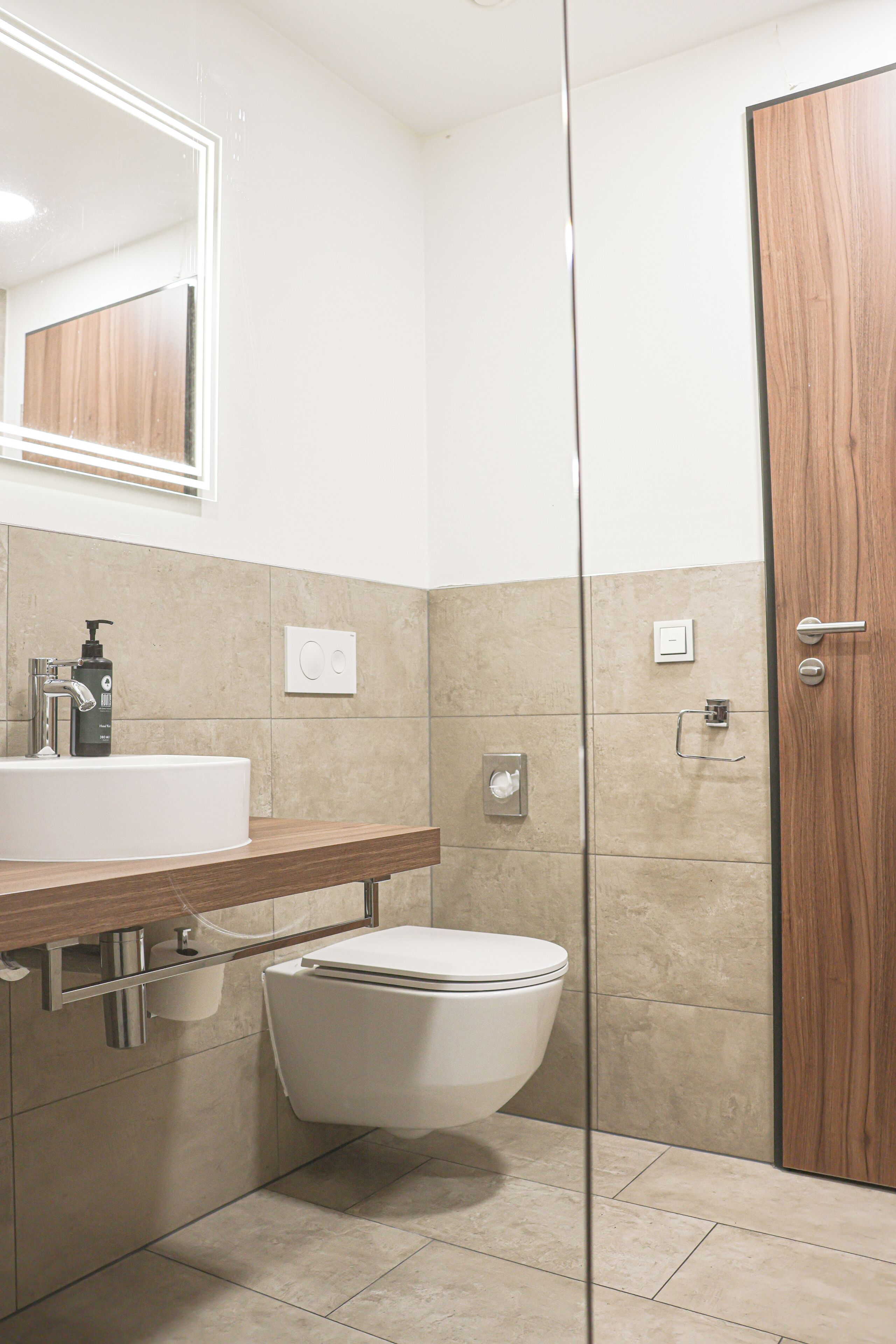Un baño con un lavamanos blanco, un inodoro y una puerta de madera.