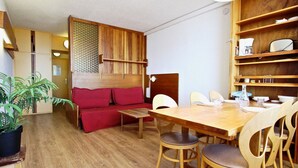 Ein gemütlicher Wohnbereich mit Holztisch, einem roten Sofa und einem Blumentopf.