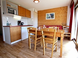 A compact kitchen with wooden cabinets, a microwave, and a dishwasher.