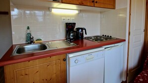 Eine kleine Küche mit Mikrowelle, Kaffeemaschine und Geschirrspüler.