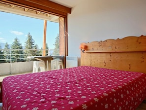 Relax in this serene retreat with a large bed and balcony overlooking trees and mountains.