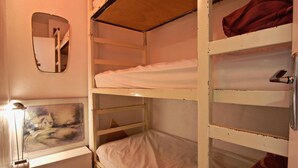 Une chambre avec un lit superposé, un tableau au mur, un miroir et une porte dotée d’une poignée.