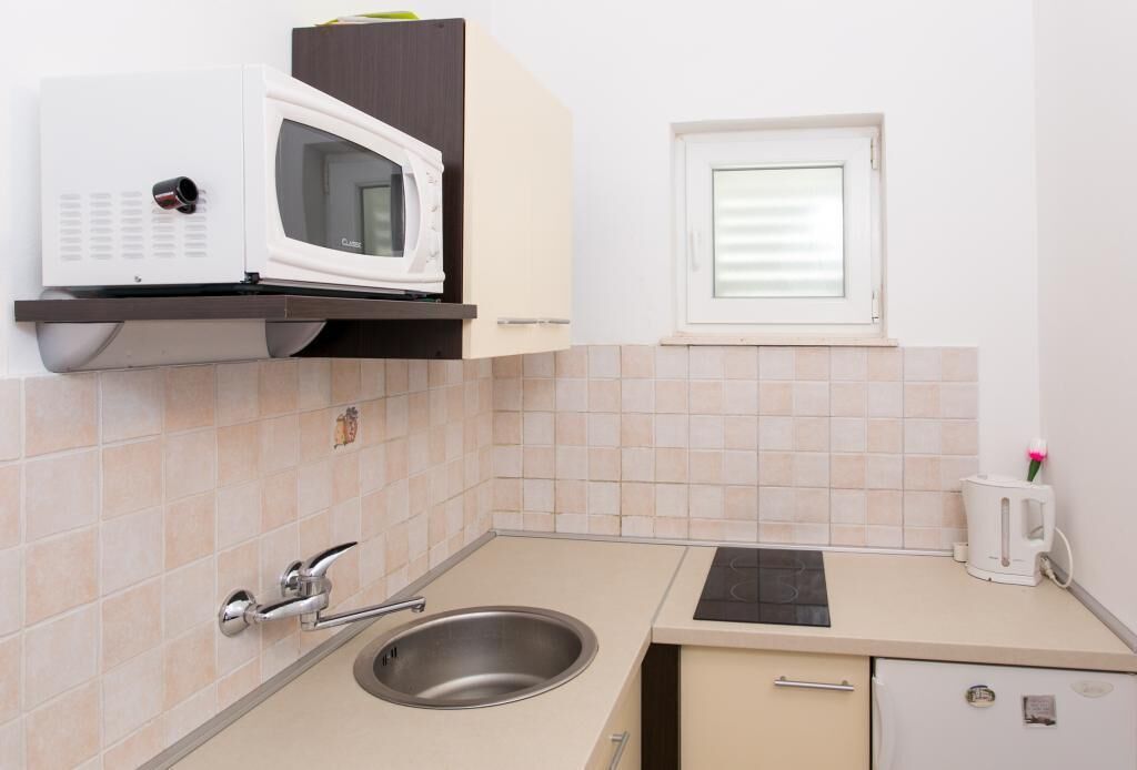 Un pequeño kitchenette con microondas, pileta y ventana.