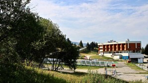 A building with a flat roof and a rectangular shape, surrounded by greenery and a clear sky. - Bright studio with loggia near slopes and shops (Chamrousse)