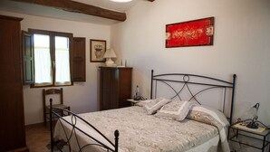 Een slaapkamer met een bed, een houten garderobe en een klein tafeltje met een lamp.