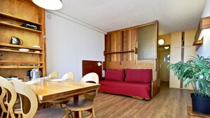 Ein gemütlicher Wohnraum mit Esstisch, Stühlen, einer Couch und einem Blumentopf.
