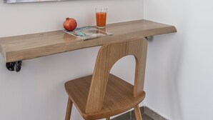 A small, modern room with a wooden desk, a chair, a mirror, and a glass of orange juice. - Michalis Studios (Milos)