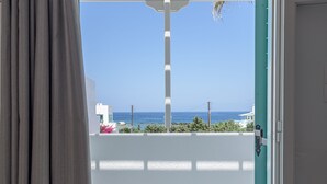A view from a balcony with a white railing, a clear blue sky, and a distant view of the sea. - Michalis Studios (Milos)