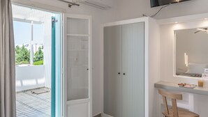 A modern bedroom with a bed, a chair, a TV, and a wardrobe. - Michalis Studios (Milos)