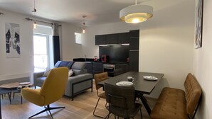 A modern living room with a dining table, sofas, and a kitchen area. - Plein centre, T3 5P totalement rénové 55m2. WIFI (Cauterets)
