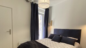 A bedroom with a bed, a door, and a window with curtains. - Plein centre, T3 5P totalement rénové 55m2. WIFI (Cauterets)