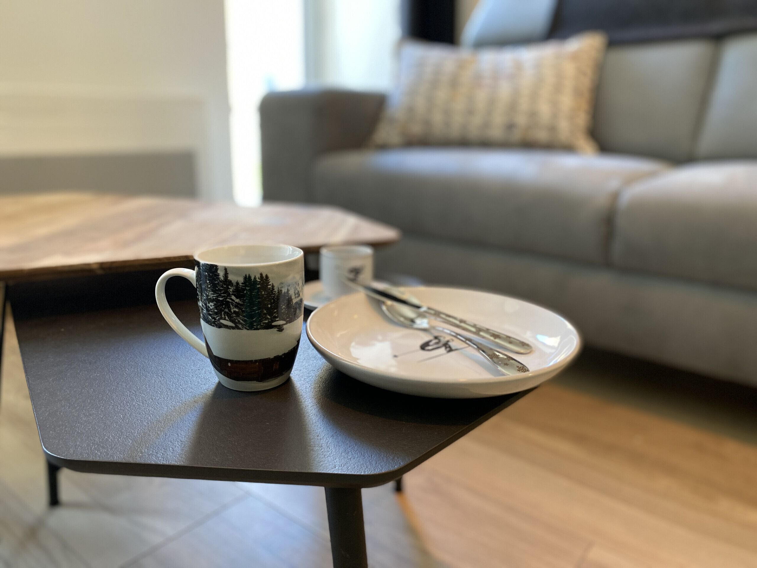 A dining table with a mug and a plate with cutlery.