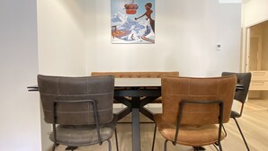 A dining area with a table and four chairs, a painting on the wall, and a wooden floor. - Plein centre, T3 5P totalement rénové 55m2. WIFI (Cauterets)