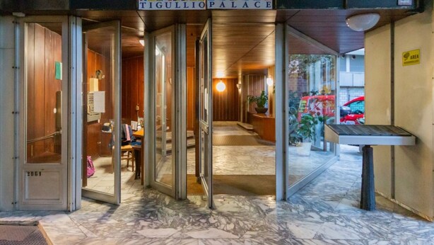 L'ingresso di un hotel con pavimento in marmo, una reception e un cartello che riporta la scritta "TIGULLIO PALACE".