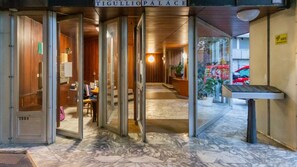 The entrance of a hotel with a marble floor, a reception desk, and a sign reading "TIGULLIO PALACE".