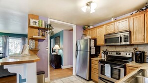 A modern kitchen with wooden cabinets, stainless steel appliances, and a tiled floor. - Dream Catcher Bungalow - Near Uptown, Bojangles Coliseum & BOA! Pet & Family Friendly, Plus 15% off! (Charlotte)