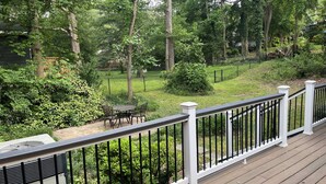 A deck with a white railing overlooking a backyard with a lawn, trees, and a patio with outdoor furniture. - Dream Catcher Bungalow - Near Uptown, Bojangles Coliseum & BOA! Pet & Family Friendly, Plus 15% off! (Charlotte)