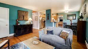 A living room with a grey sofa, wooden coffee table, and a dining area with a table and chairs. - Dream Catcher Bungalow - Near Uptown, Bojangles Coliseum & BOA! Pet & Family Friendly, Plus 15% off! (Charlotte)