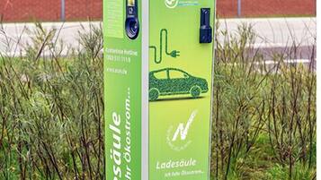 A green electric vehicle charging station with a car icon, a plug symbol, and the text "Ladesäule" and "Ich fahre Ökostrom."