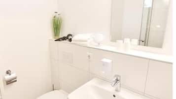A modern bathroom with a toilet, sink, and mirror.