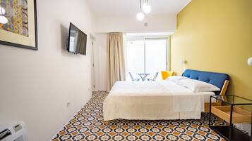 Quarto com cama, televisão, janela com cortinas e piso estampado.