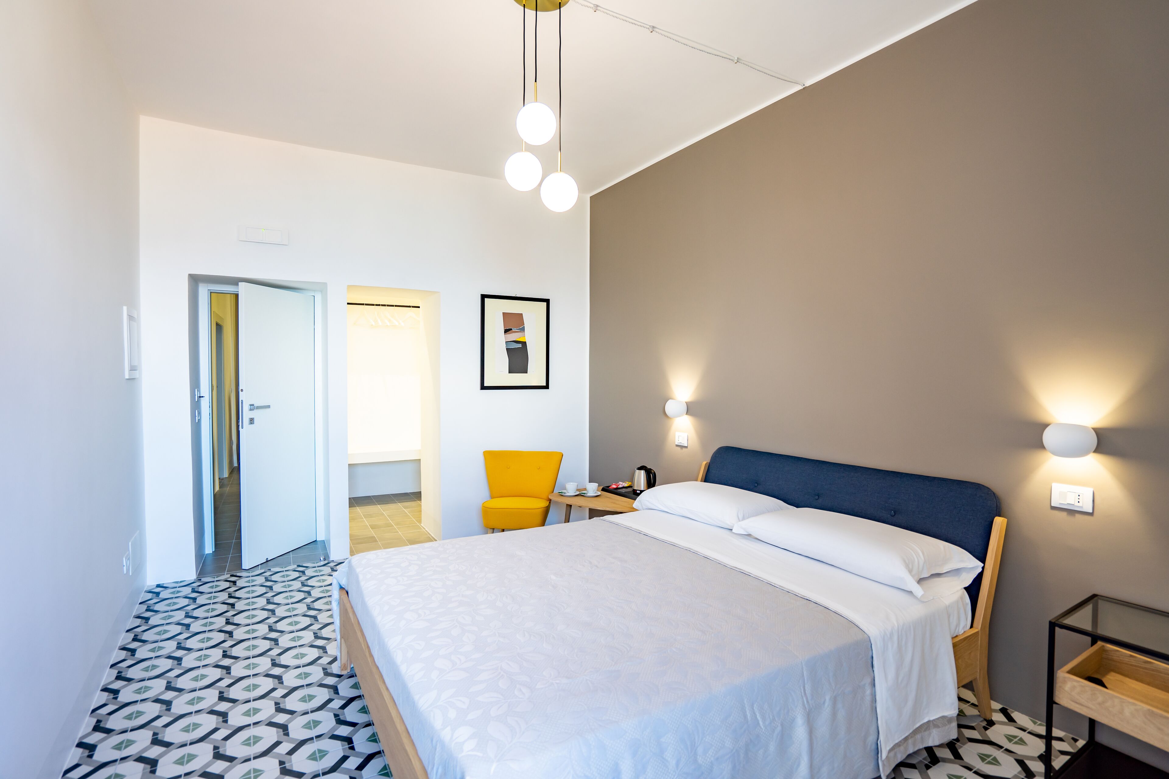 Una camera d'albergo moderna con un letto grande, una sedia, una scrivania e un quadro appeso al muro.