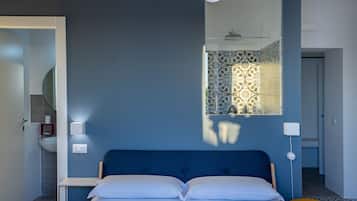 A bedroom with a bed, bedside lamps, a mirror, and a window with patterned curtains.