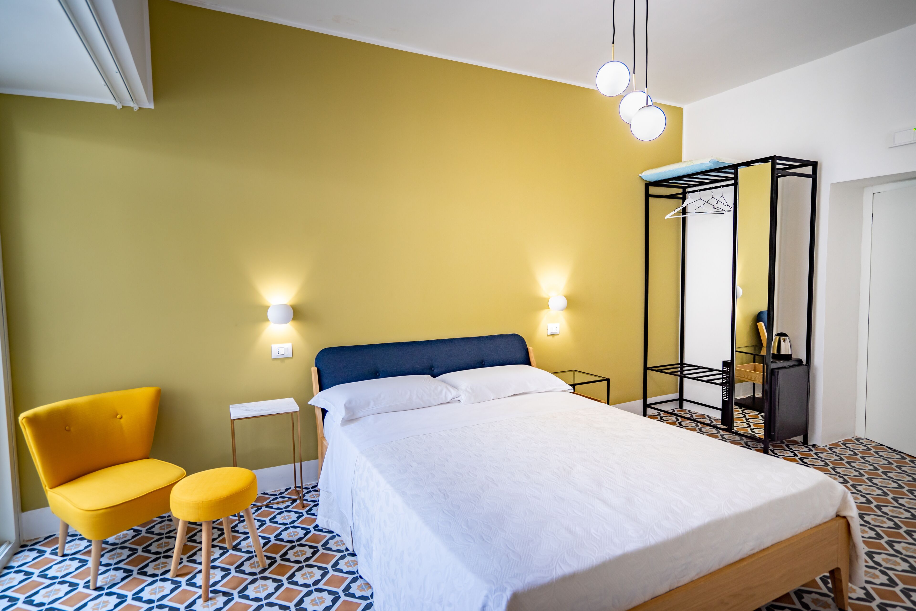 Um quarto com uma cama, uma cadeira, um guarda-roupa e uma pequena mesa.