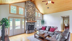 A spacious living room with a stone fireplace, wooden ceiling, and large windows. - Mtn Views & Hot Tub: 6-Acre Blue Ridge Retreat! (Swannanoa)