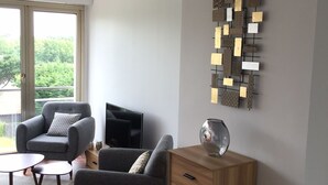 Una sala de estar moderna con un sofá gris, un mueble de madera y una obra de arte en la pared.