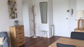 Un área de comedor moderna con una mesa y sillas de madera, un sofá gris, un aparador de madera y un adorno en la pared.