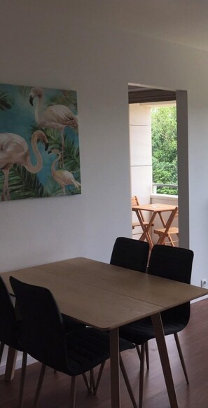 Enjoy meals in this stylish dining area with a large painting of flamingos and a doorway leading to an outdoor space.