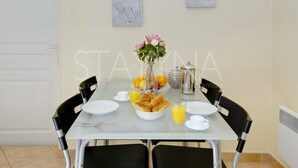 Spisebord dækket med tallerkner, en skål med croissanter, en vase med blomster, et tekopper og et kande appelsinjuice.