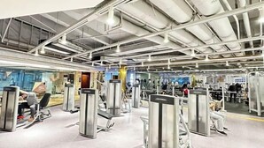 Een fitnessruimte met diverse trainingsapparaten en een grote spiegelwand.