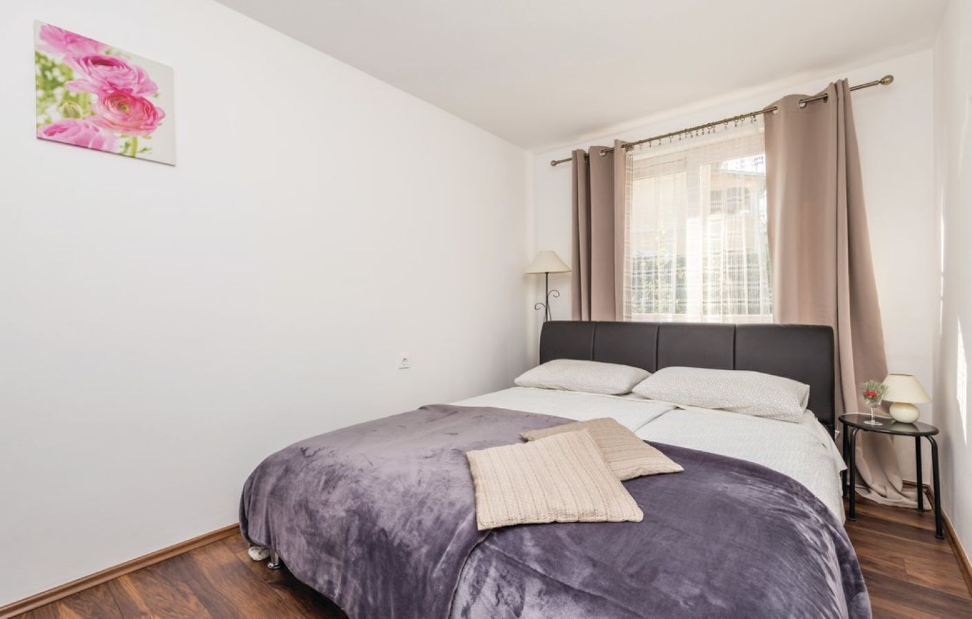 A bedroom with a bed, a nightstand, a lamp, and a window with curtains.