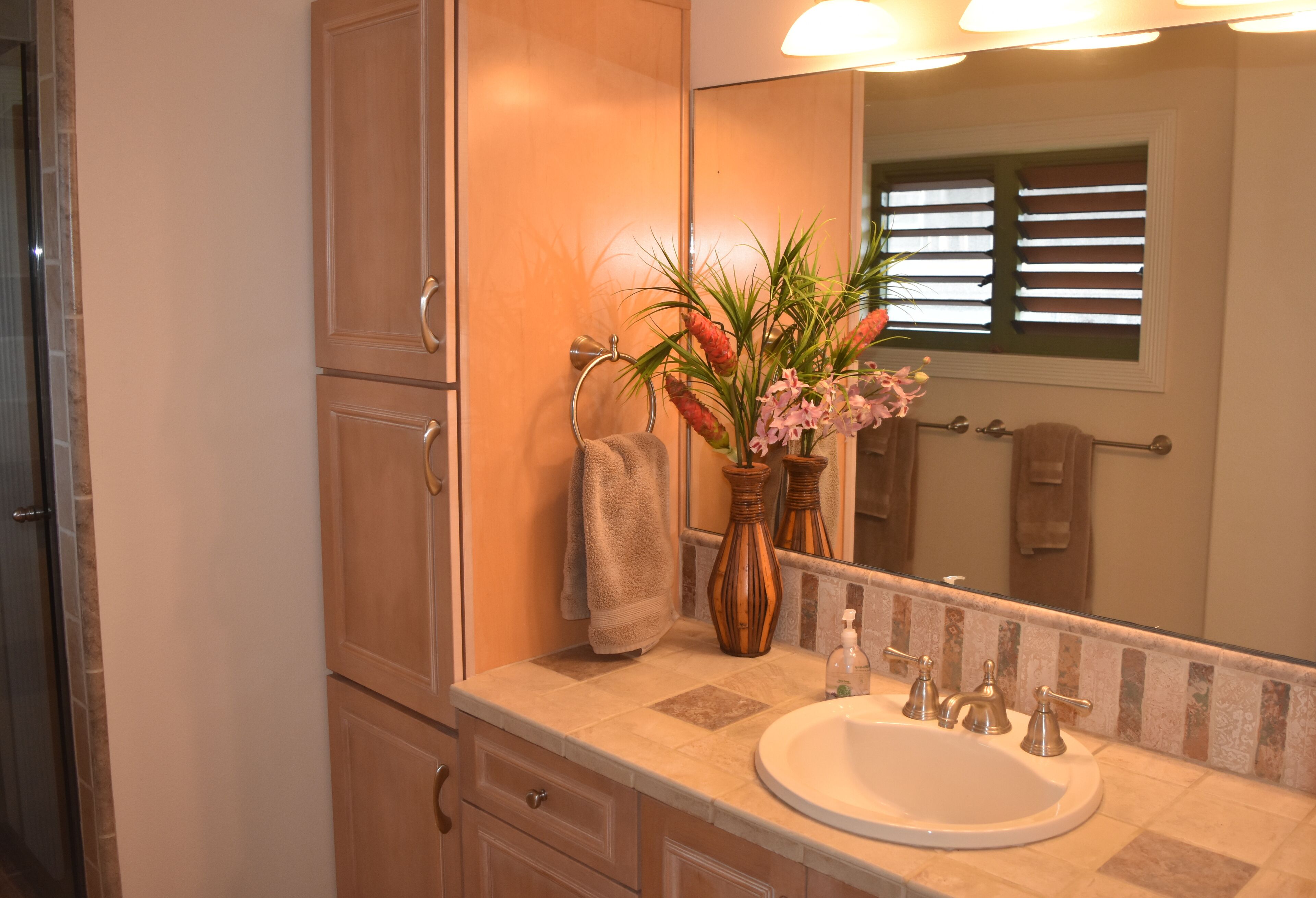 A bathroom with a sink, mirror, towel rack, and cabinets.