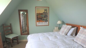 Un dormitorio con una cama, una silla, una mesita de noche, una lámpara y un cartel en la pared.