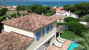 Une villa avec un toit en tuiles, une piscine et une vue sur la mer.