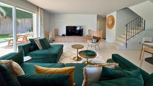 Una sala de estar moderna con un juego de sofá verde, un televisor de pantalla plana y un comedor con una mesa de madera.