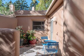 A patio with a table and chairs, potted plants, and a window. - Spacious, Historic Downtown Jewel, Walk Everywhere (Santa Fe)