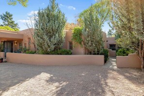 A courtyard with a gravel path, surrounded by low walls and various shrubs and trees. - Spacious, Historic Downtown Jewel, Walk Everywhere (Santa Fe)