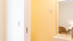 Kylpyhuone, jossa on valkoinen wc-istuin, keltainen allaskaappi ja peili.