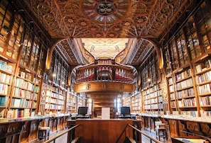A library interior with ornate woodwork, bookshelves, and a central reading area. - Clerigos Tower - Experience in Porto (Porto)